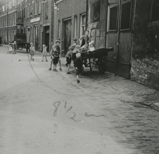 876880 Afbeelding van een groep kinderen, spelend op en rond een handkar in de Bergstraat in Wijk C te Utrecht.N.B. De ...